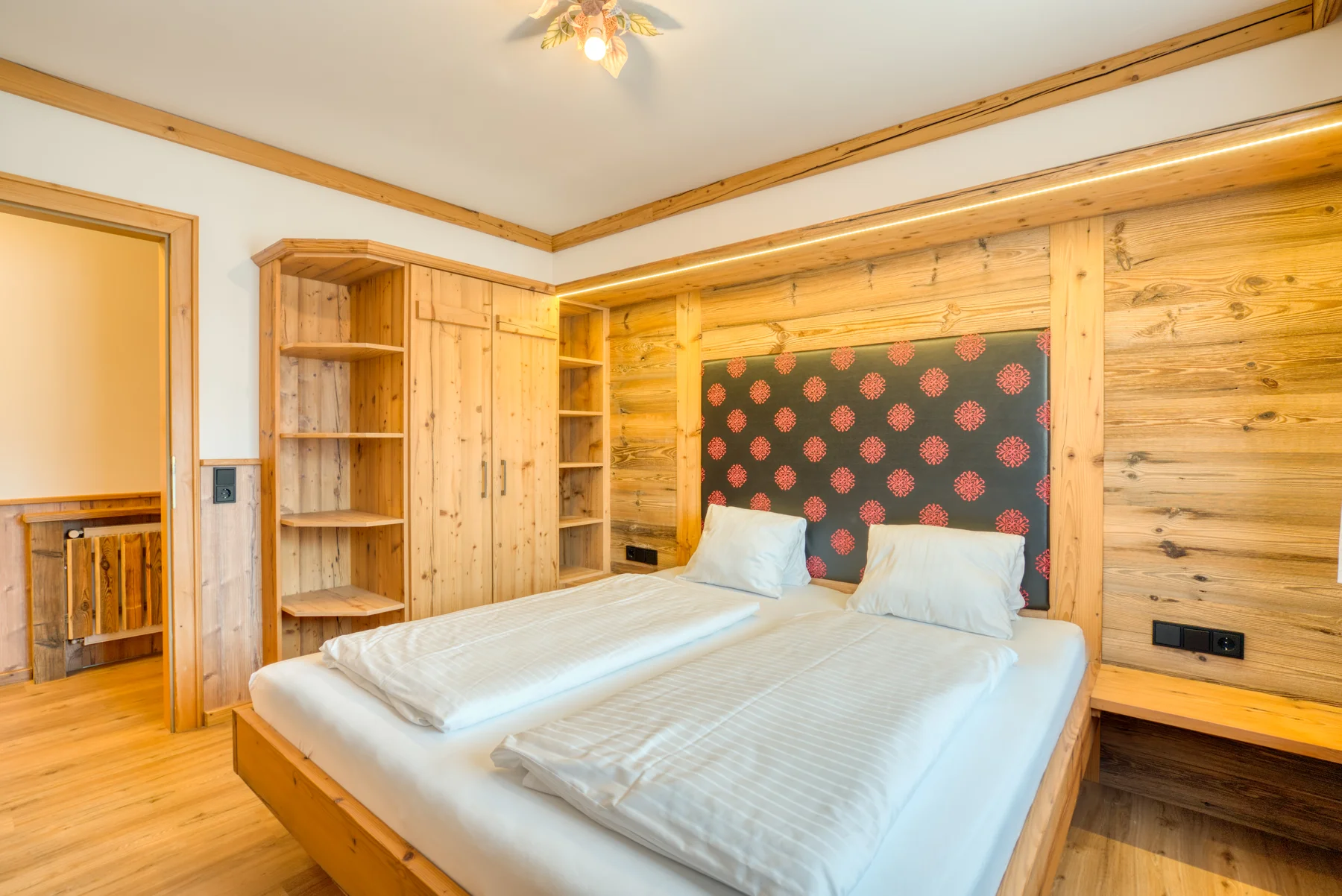 Schlafzimmer mit Altholz und weißer Bettwäsche im Appartement Hofmann